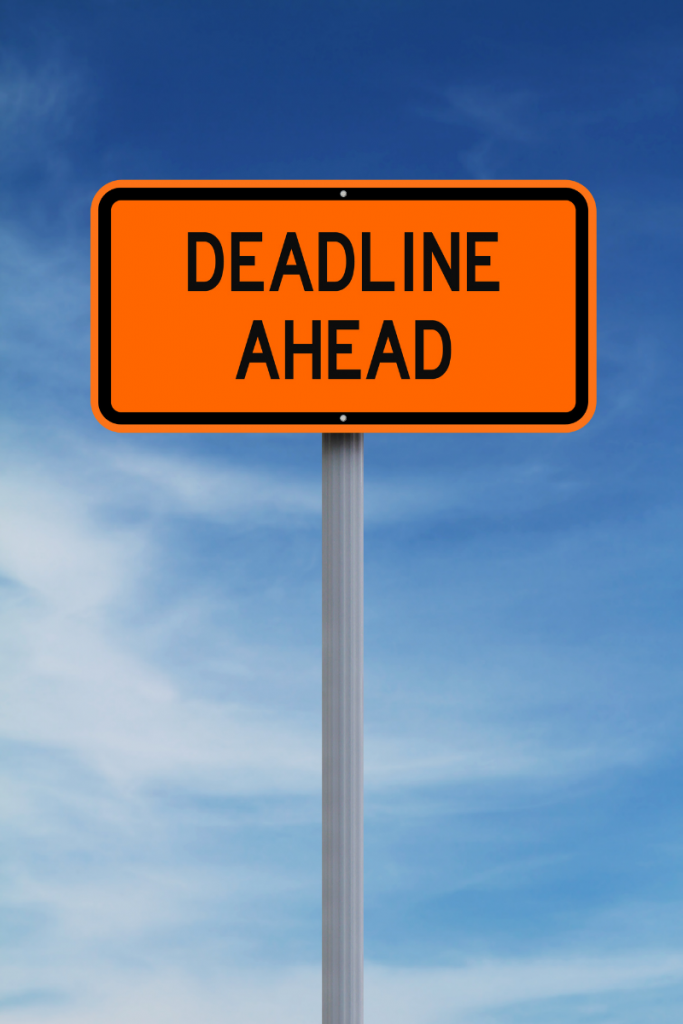 The background is a blue sky. On a silver pole is an orange sign that says Deadline ahead in black writing. 
